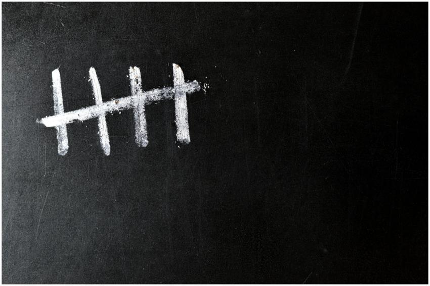 Five chalk tally marks on a black chalkboard backg