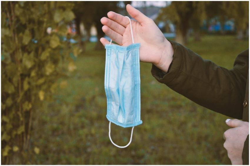 A person holds a blue face mask outside, highlight