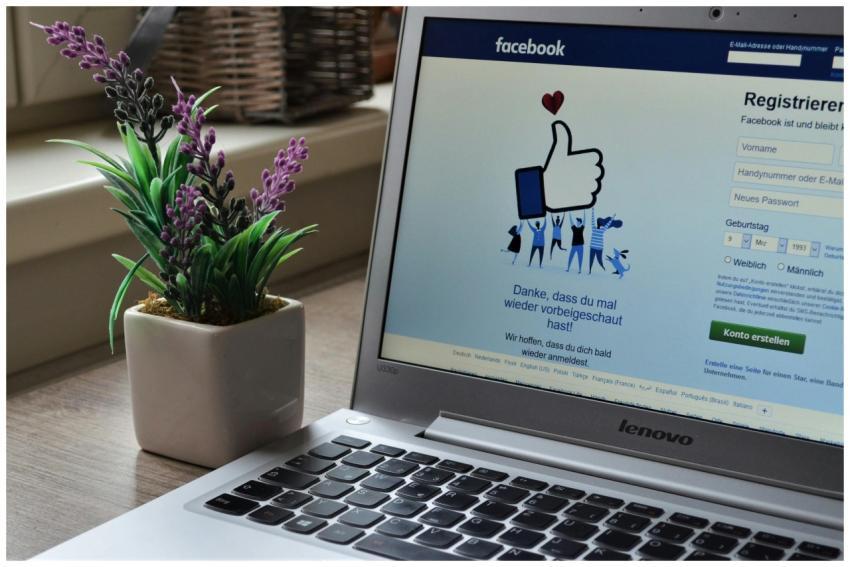 A Lenovo laptop displaying Facebook login beside a