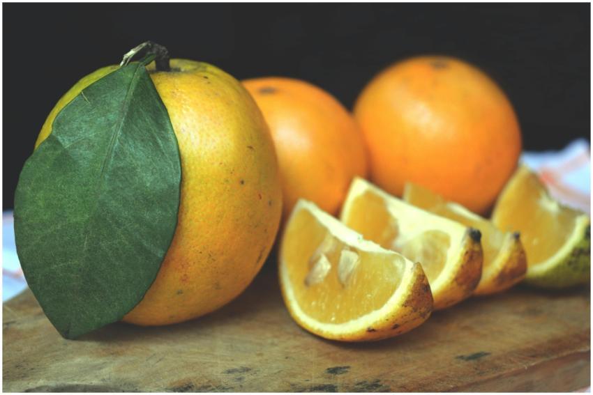 Close-up of ripe oranges and slices on a wooden bo