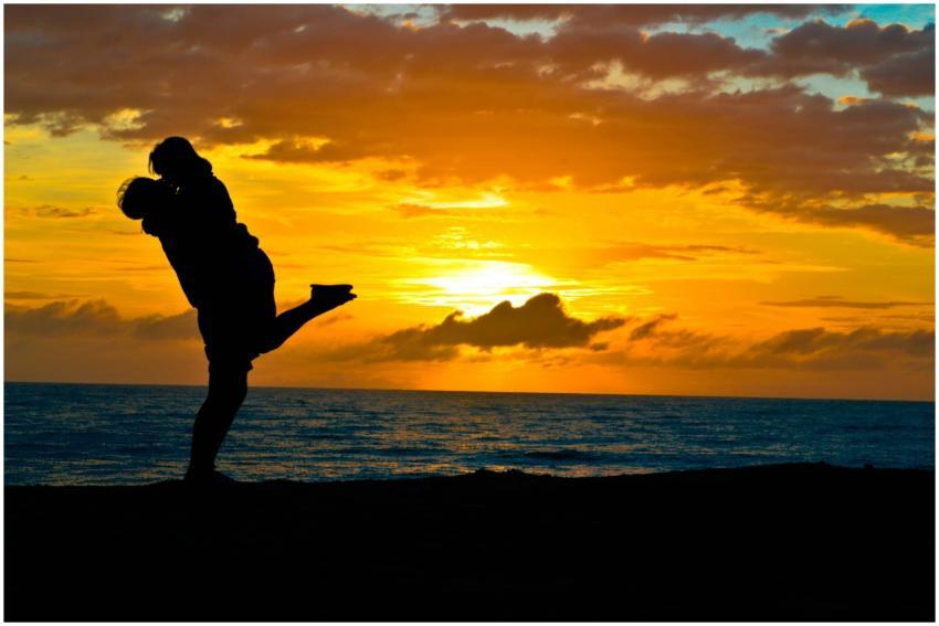 Silhouette of a romantic couple embracing on a bea