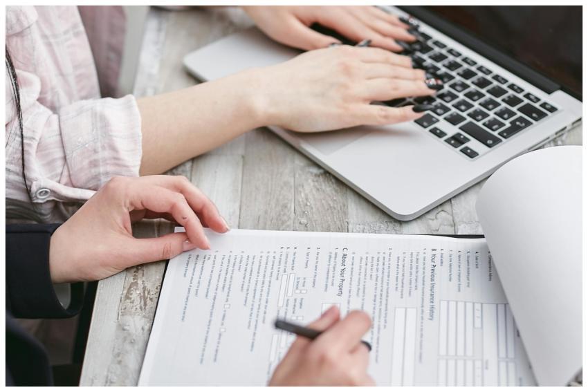 Close-up of hands typing on a laptop and reviewing