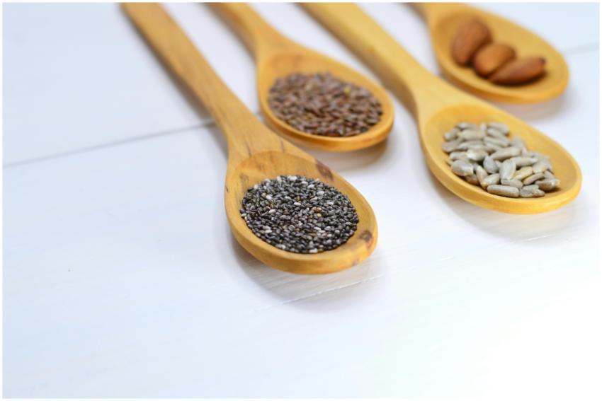 A variety of seeds and nuts in wooden spoons displ