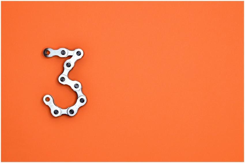 A bicycle chain forms the number three against a v