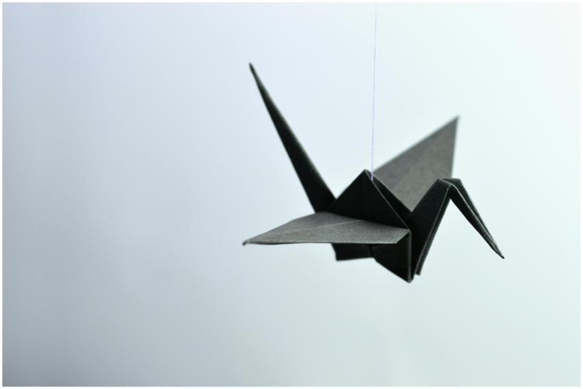A minimalist black origami crane elegantly suspend