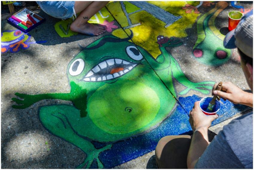 Colorful street art of a cartoon frog being painte