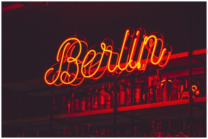 Illuminated Berlin neon sign above a shelf of alco