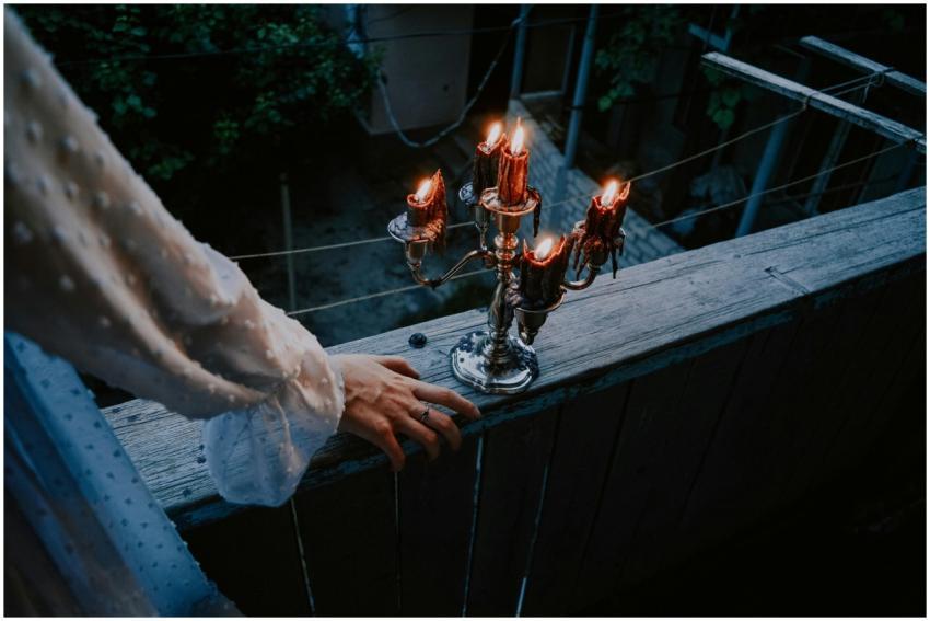 A mysterious hand reaches towards a burning candel