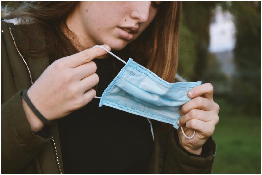 Young woman holding a face mask outdoors, represen
