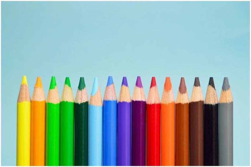 A row of vibrant colored pencils lined up on a sof
