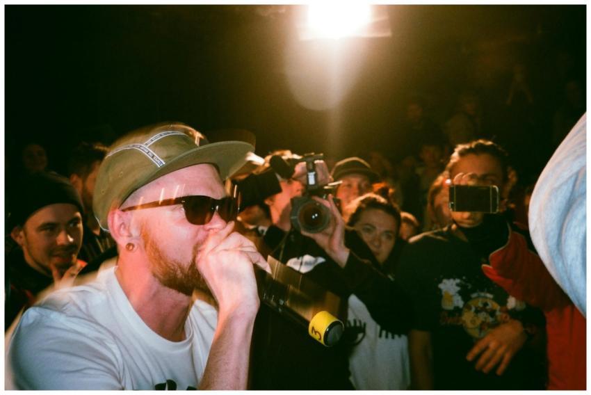 A rapper performs on stage with a vibrant crowd an