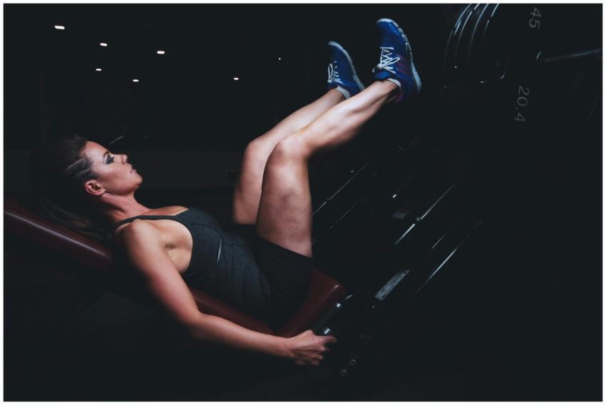 Focused woman doing leg press exercise in a dimly