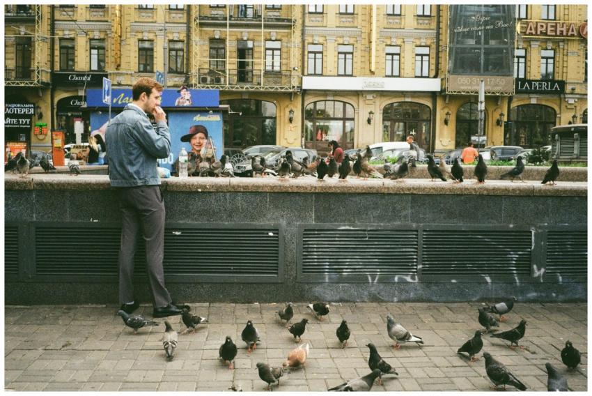 A man in a denim jacket stands in Kyiv surrounded