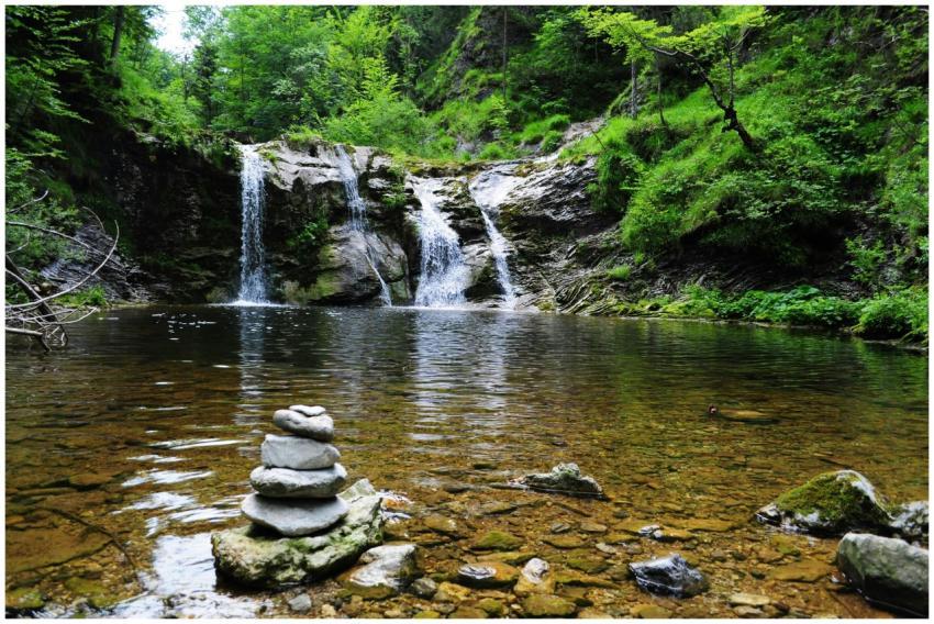 Peaceful forest waterfall with serene stone cairn,