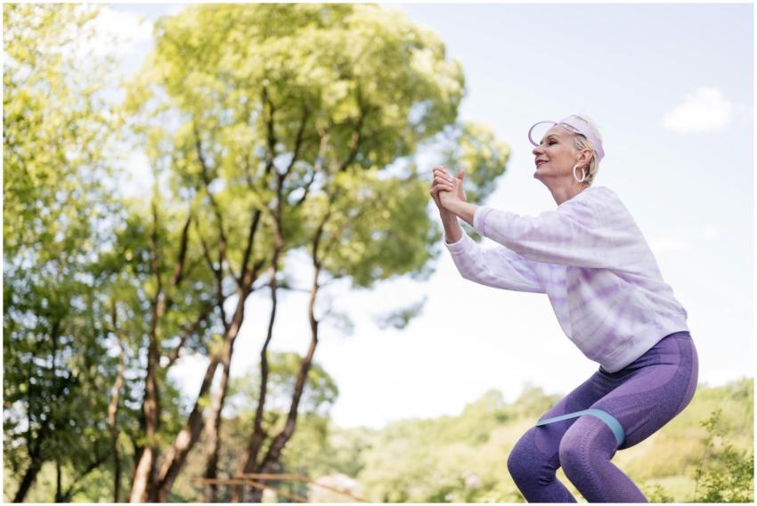 A senior woman exercises in a park with a resistan