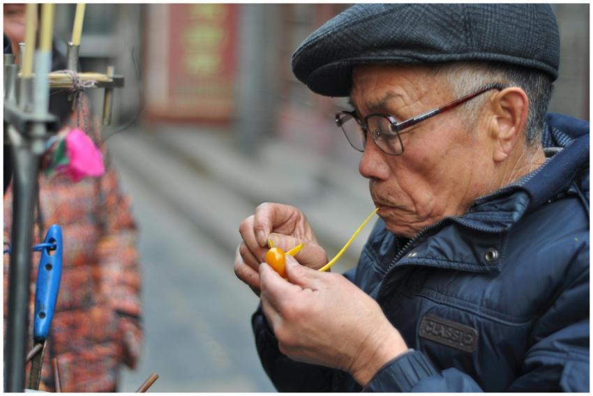 Elderly man creating intricate sugar candy on a st