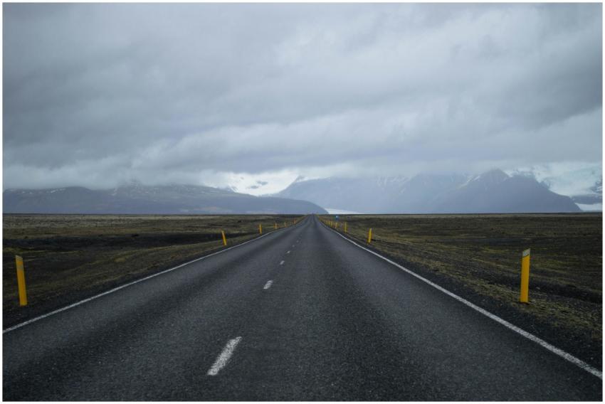 A long empty road stretches towards snow-capped mo