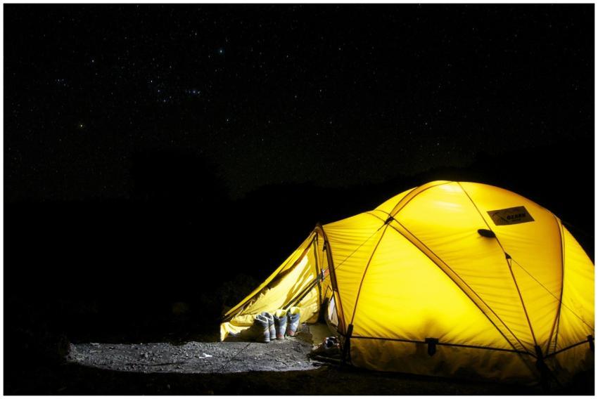 A glowing yellow tent pitched outdoors under a vas