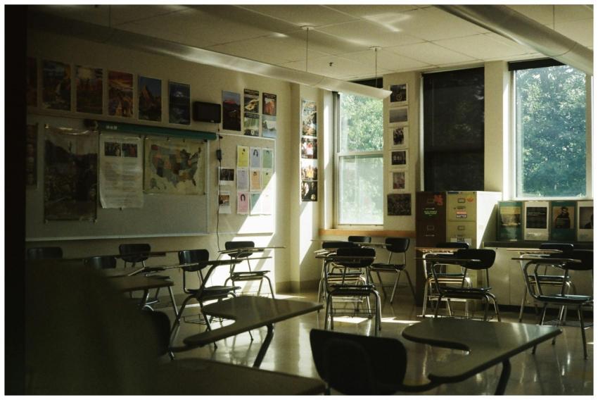 A sunlit classroom with empty desks, chairs, and e