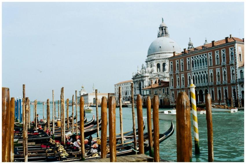 Dock with gondolas with wooden pillars moored on c
