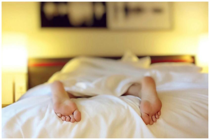 A person relaxing on a bed with feet under white s
