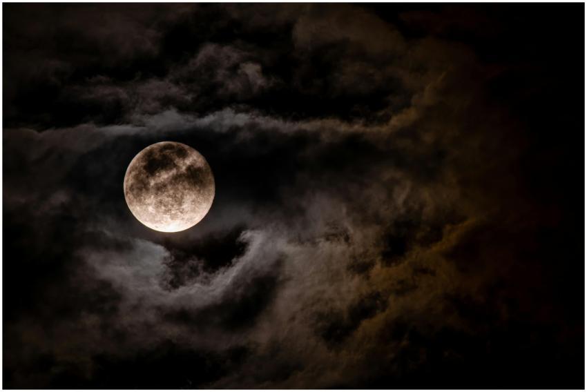 Captivating full moon obscured by dark clouds in a
