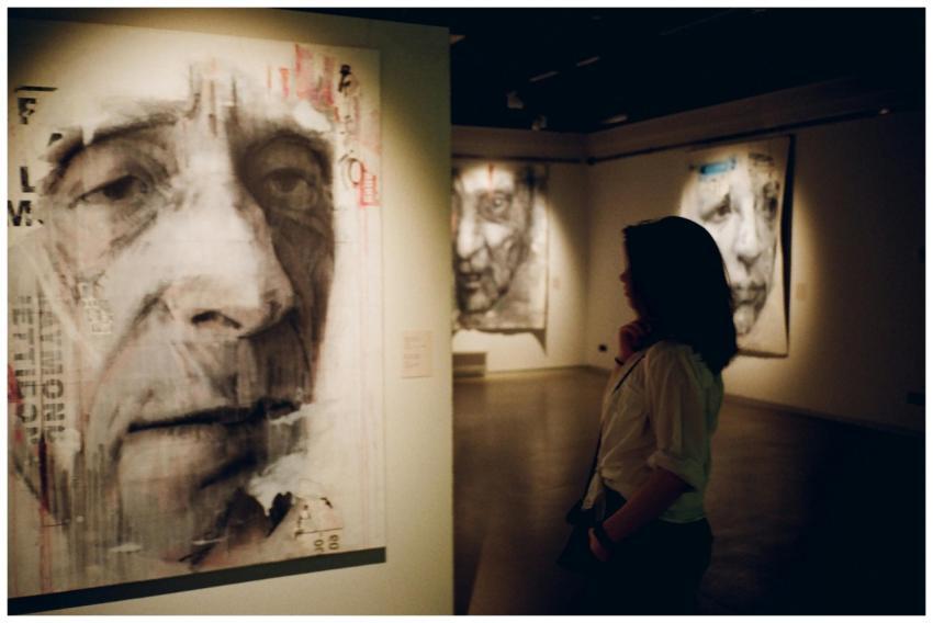 A woman observes portrait paintings in a dimly lit