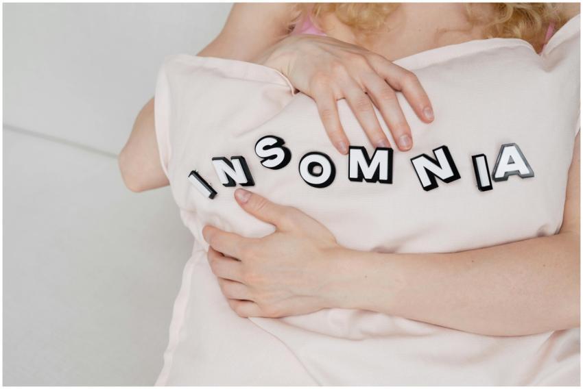 Close-up of a woman holding a pillow with 'insomni