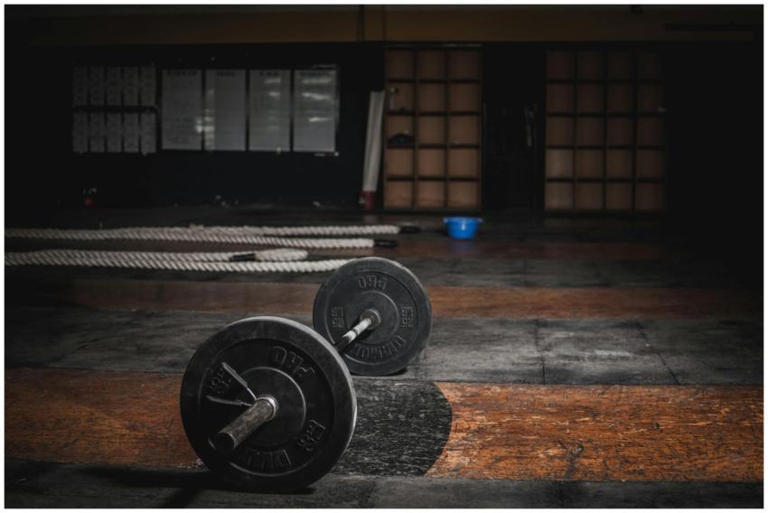 A lone barbell rests in an empty, dimly lit gym, e
