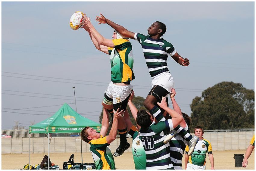 Energetic rugby players leap for the ball during a