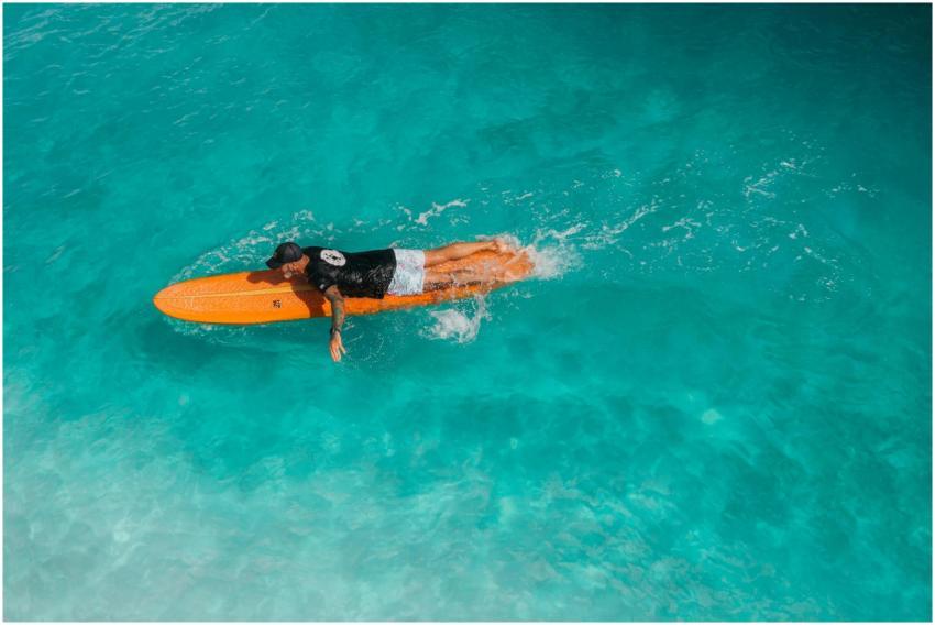 Man paddling on surfboard in tropical ocean, captu