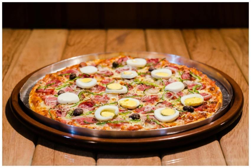 Mouth-watering pizza topped with eggs and meat, pe