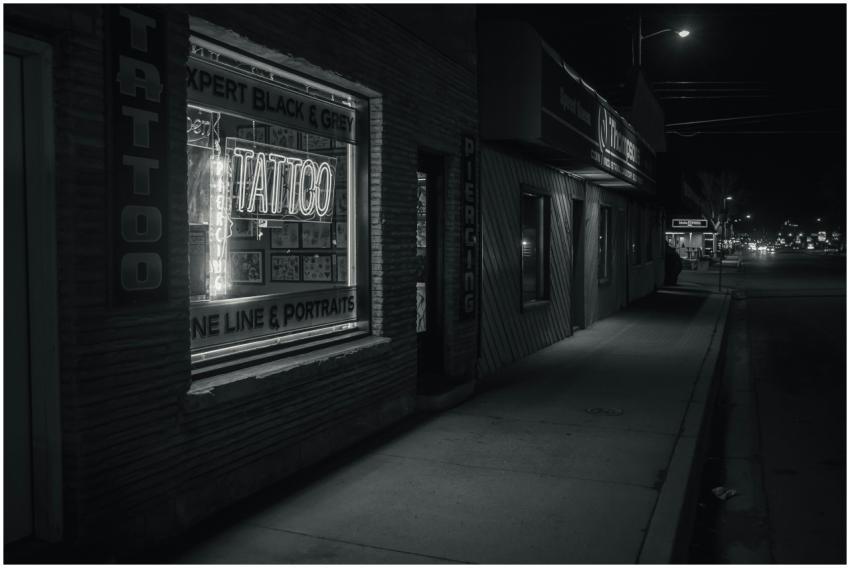 Black and white night view of a tattoo shop window
