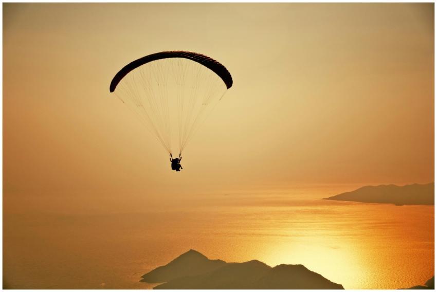 A silhouette of a paraglider flying over the stunn