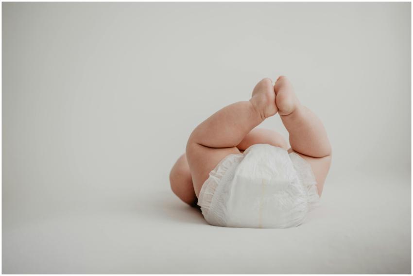 Cute baby lying on back in a diaper against a soft