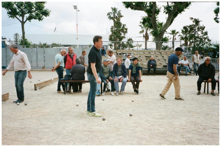 A diverse group of men playing petanque on an outd