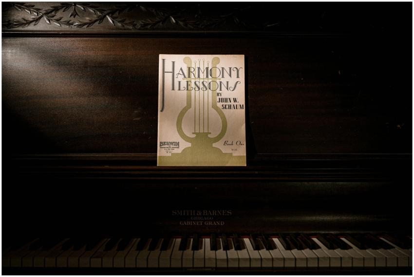 Dark, vintage piano with 'Harmony Lessons' sheet m