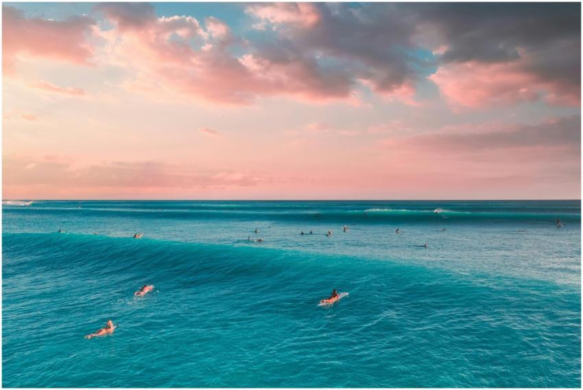 A group of surfers catching waves under a beautifu