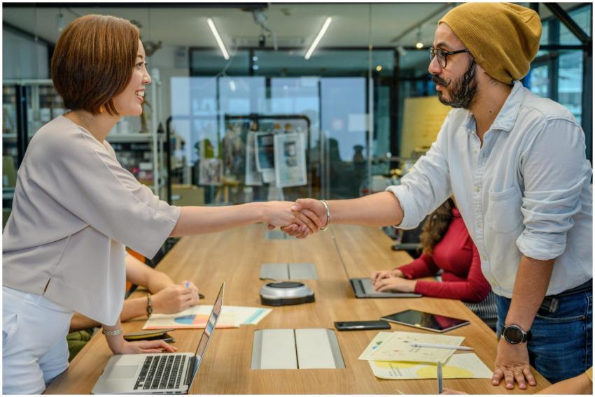 Two professionals shaking hands over a meeting tab