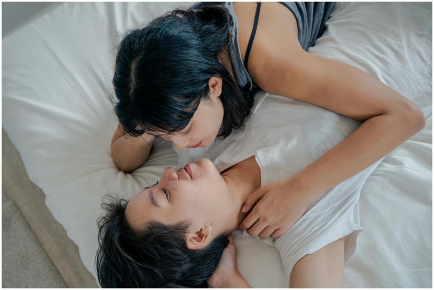 A loving moment between two Asian women lying toge