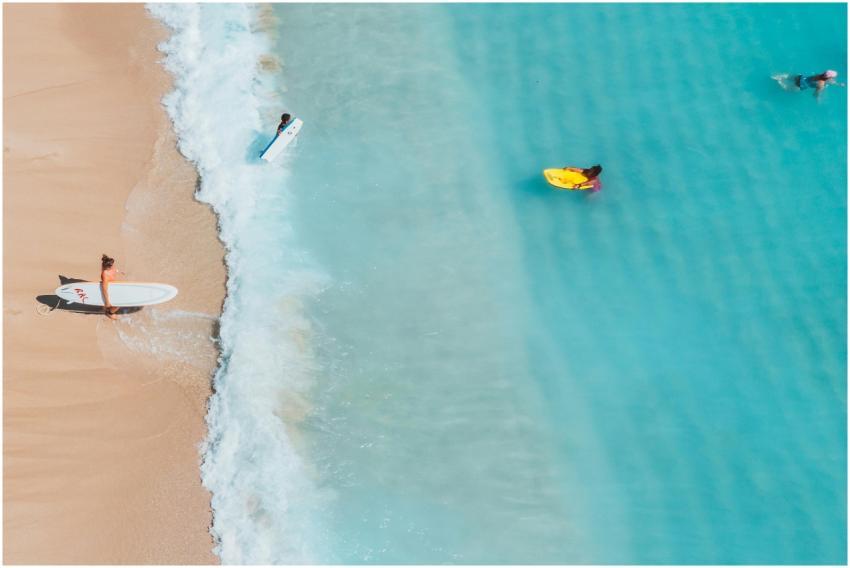 Aerial shot of surfers enjoying a sunny day on a p