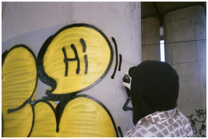 A street artist spray paints colorful graffiti wit