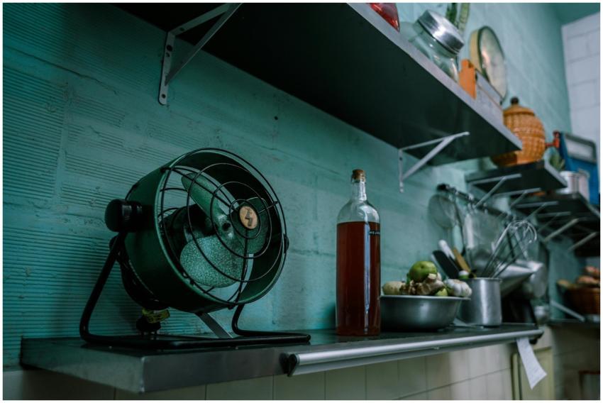 A rustic kitchen scene featuring a vintage fan, co