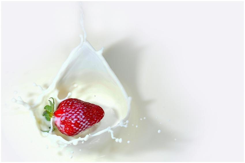 Vibrant strawberry captured splashing into milk, c