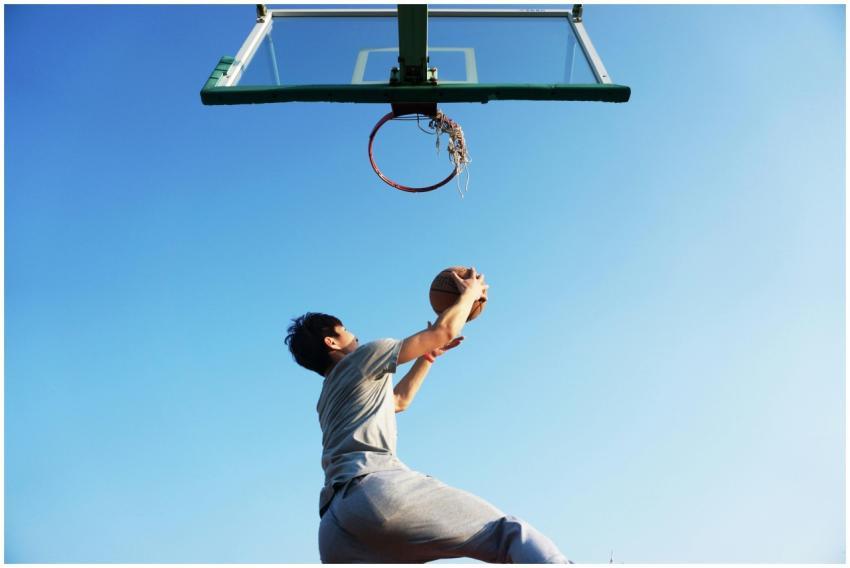 A young man jumping to dunk a basketball outdoors