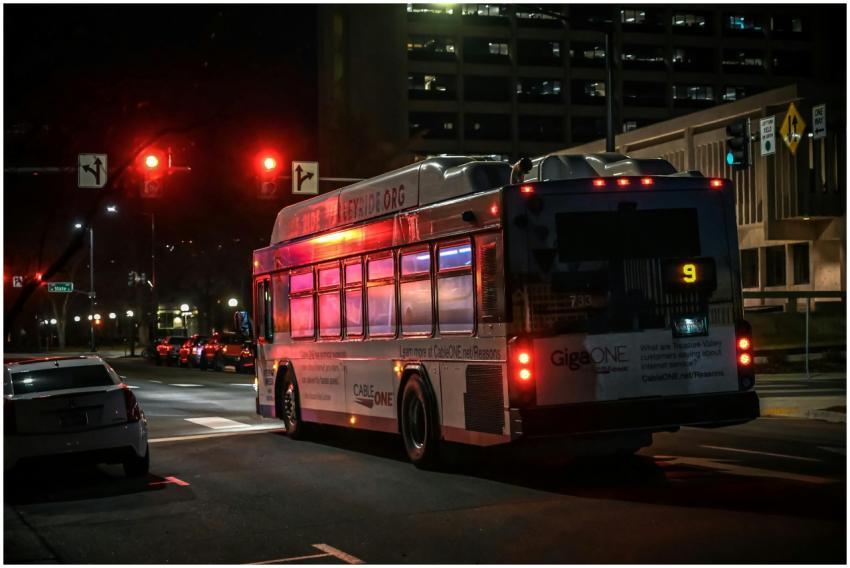 A city bus stopped at a traffic light during the n