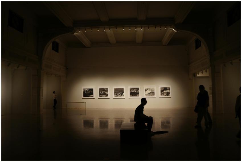 A dimly lit gallery showcasing silhouettes and fra