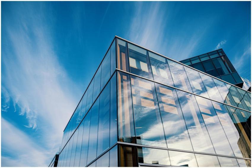 Sleek glass facade reflecting clouds in a modern a