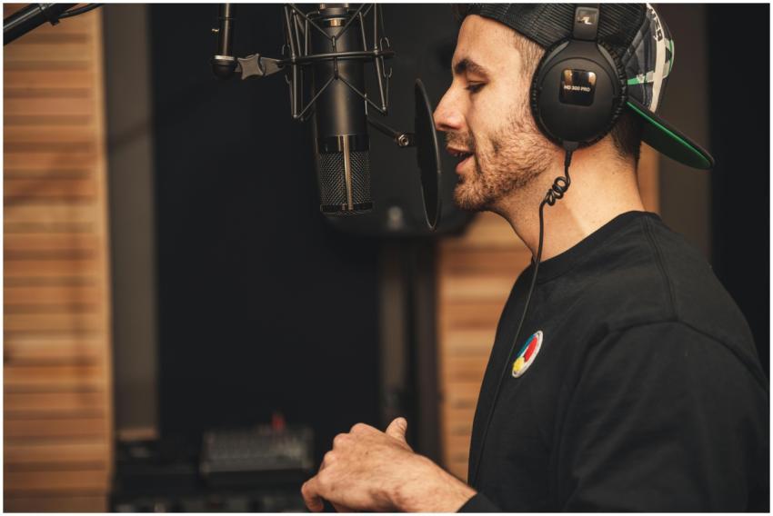 A man wearing headphones and recording vocals in a