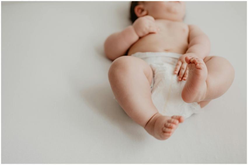 Cute baby lying on a white surface in a diaper, sh
